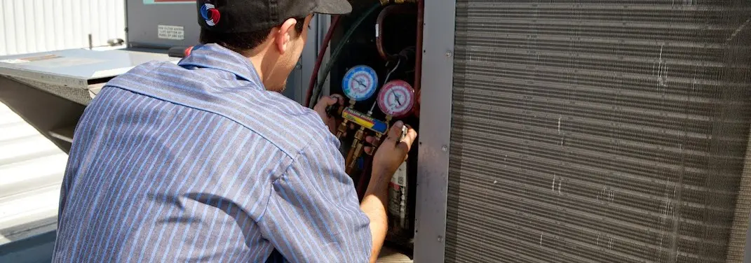 HVAC technician servicing a condenser unit in Rantoul
